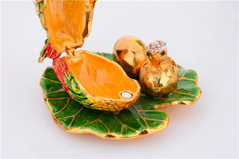 A colorful jewelry box depicting the shape of a hen laying eggs